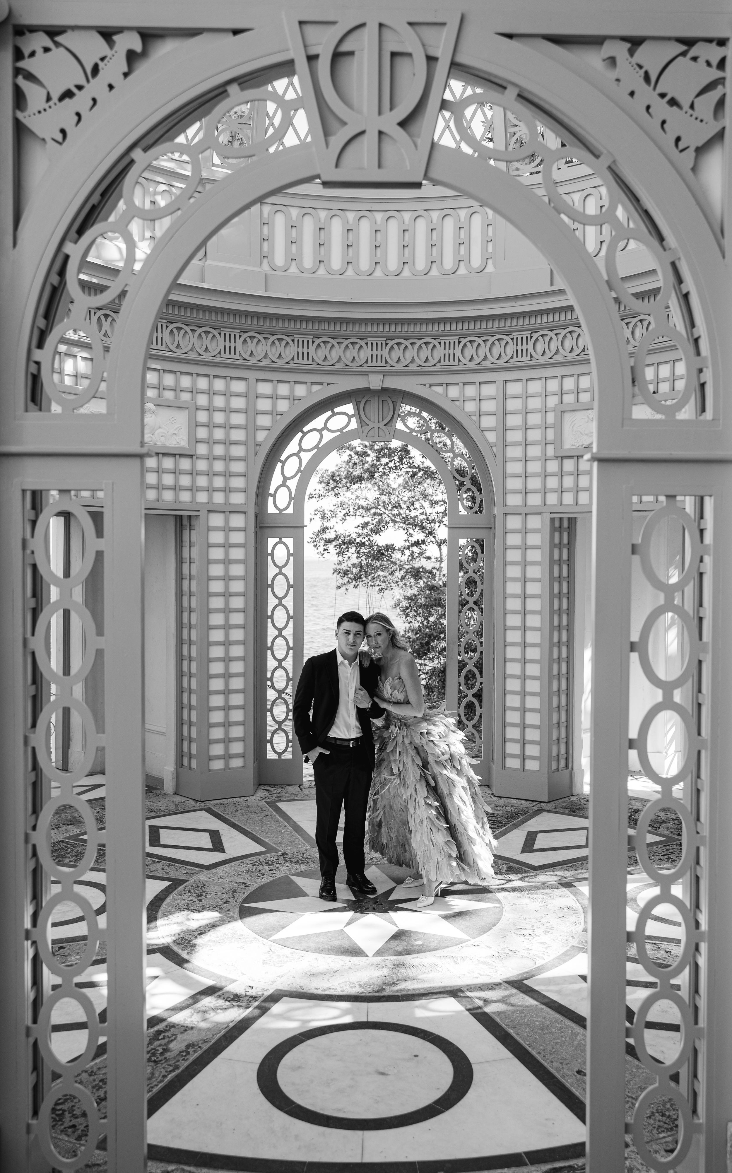 A romantic portrait through intricate archways in a classical pavilion with geometric patterns.