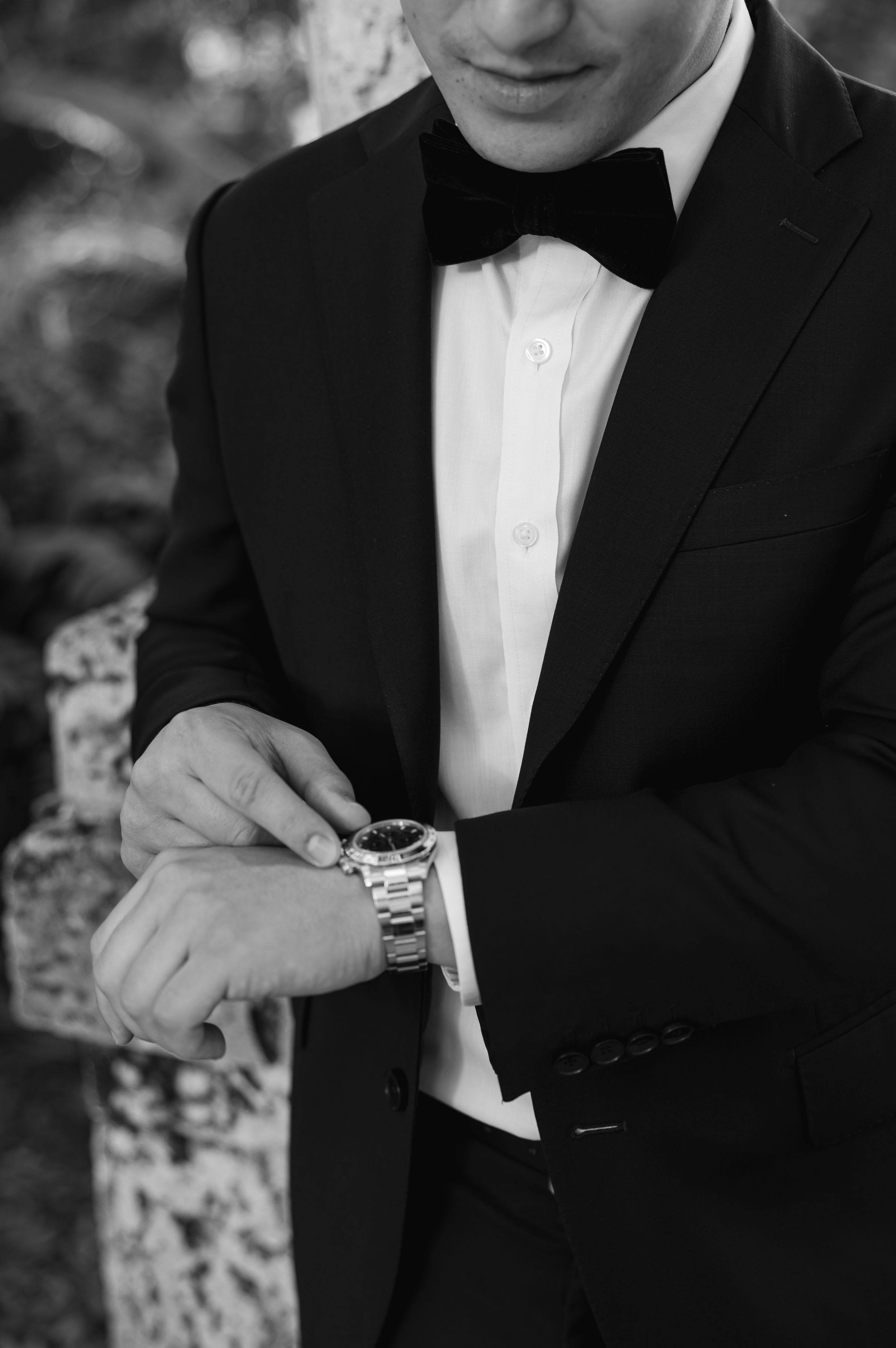 Close-up of a groom in a tuxedo adjusting his watch.