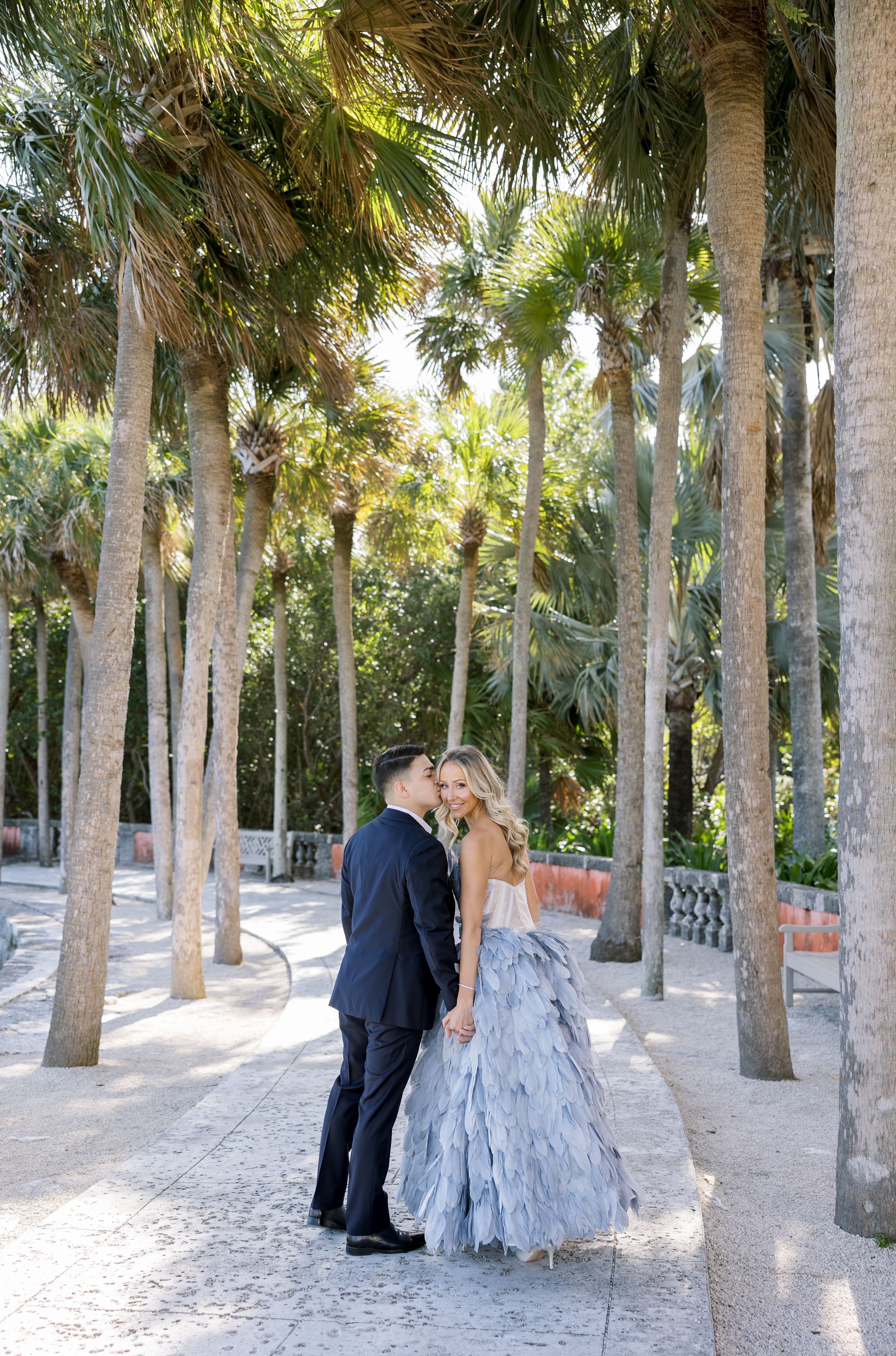Couple sharing romantic moment among palm trees in tropical garden setting.