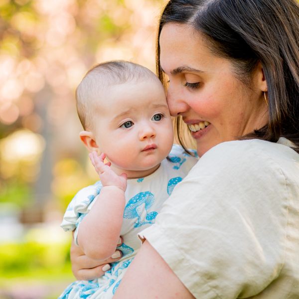 A mother snuggles her nose against her baby's forehead in a Chevy Chase park at a family photo session.