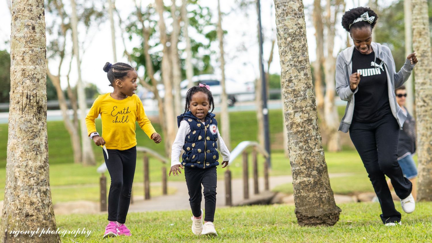 People running together between palm trees in an outdoor park setting.