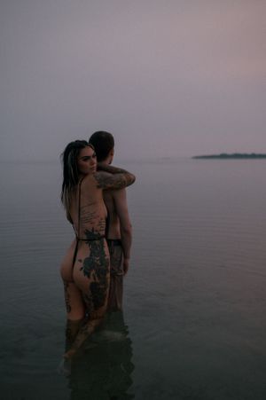Two people embracing in calm ocean waters at twilight.