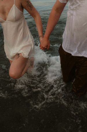 People splashing water in the ocean while wearing white clothing.