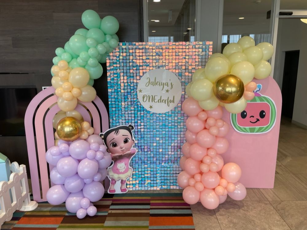 Cocomelon theme backdrops and shimmer wall with pink purple yellow mint color balloons and character cutouts, cake stands
