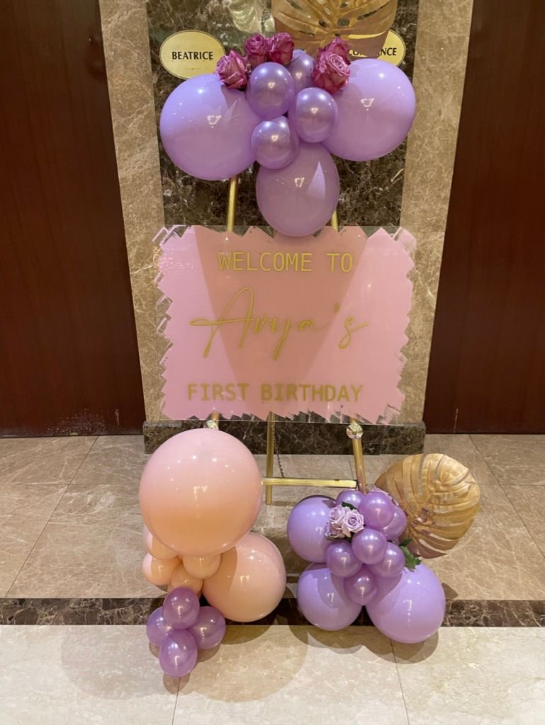 Entry way easel for a first birthday party decor with pink and purple balloons