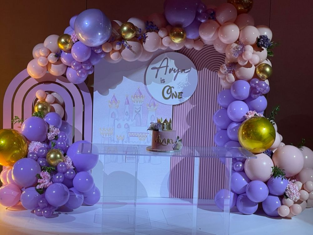 First birthday party stage decor with personalized name, pink and purple balloons, and a ghost table