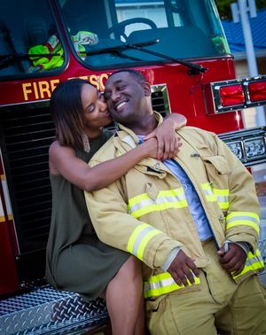 A romantic moment shared between two people by a fire truck.