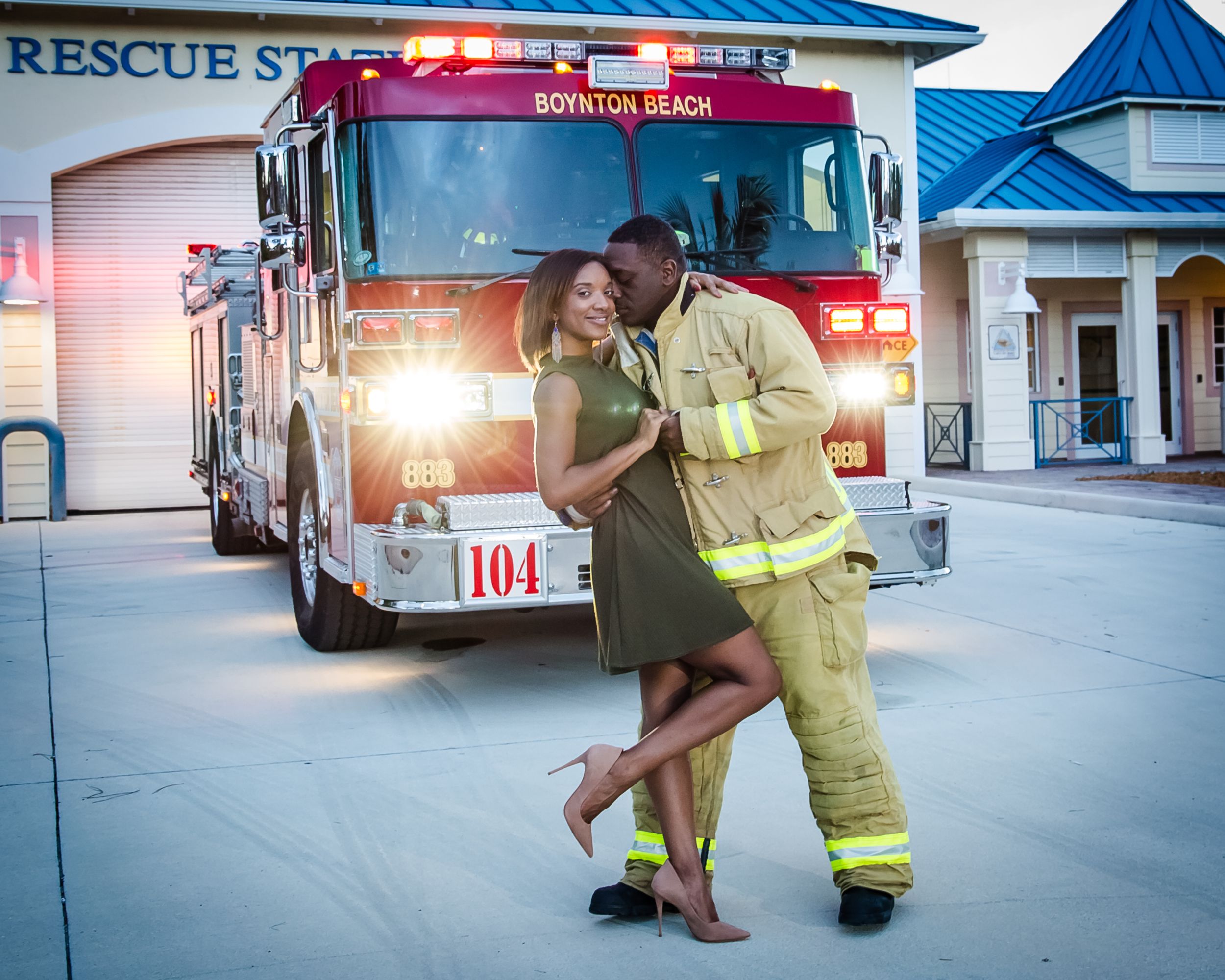 A couple embraces and dances in front of a fire truck at a rescue station.