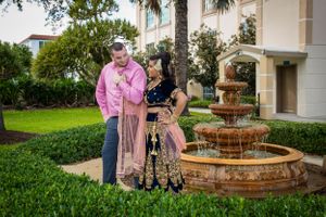 A couple shares a romantic moment near a decorative fountain in a landscaped garden.