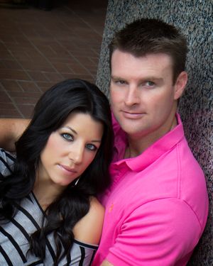 A couple poses against a textured wall in coordinated casual outfits.