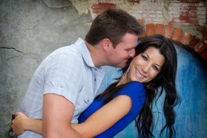 A romantic moment captured against a weathered wall with blue paint.