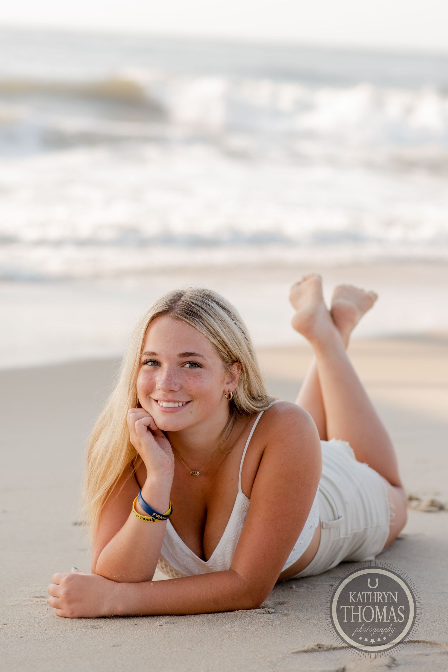 A relaxed beach portrait of someone lying on sand with waves in the background.