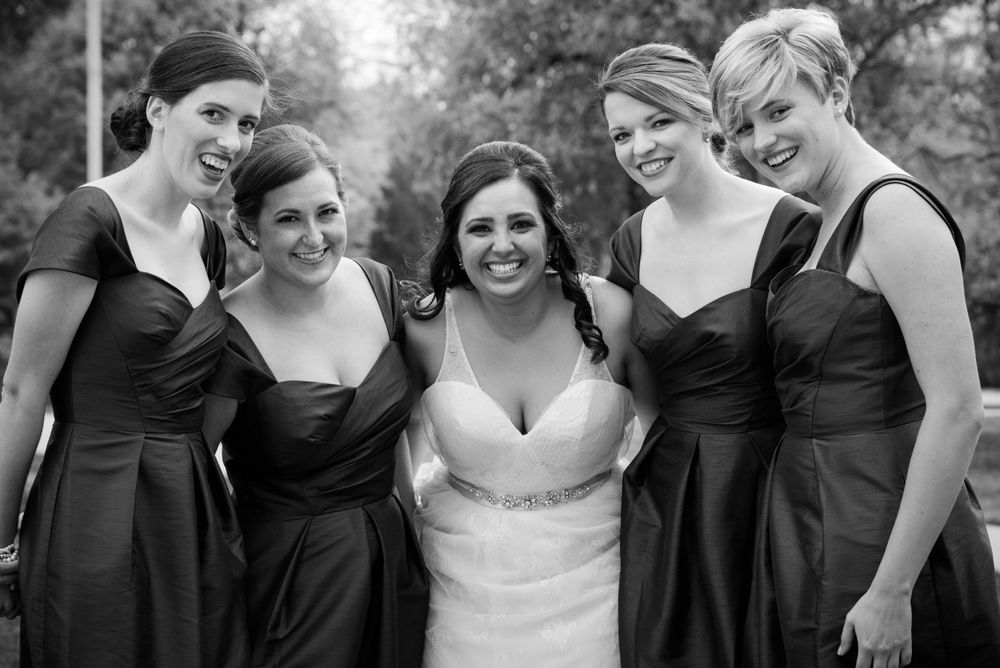 A black and white wedding photo with a group wearing matching dark dresses.