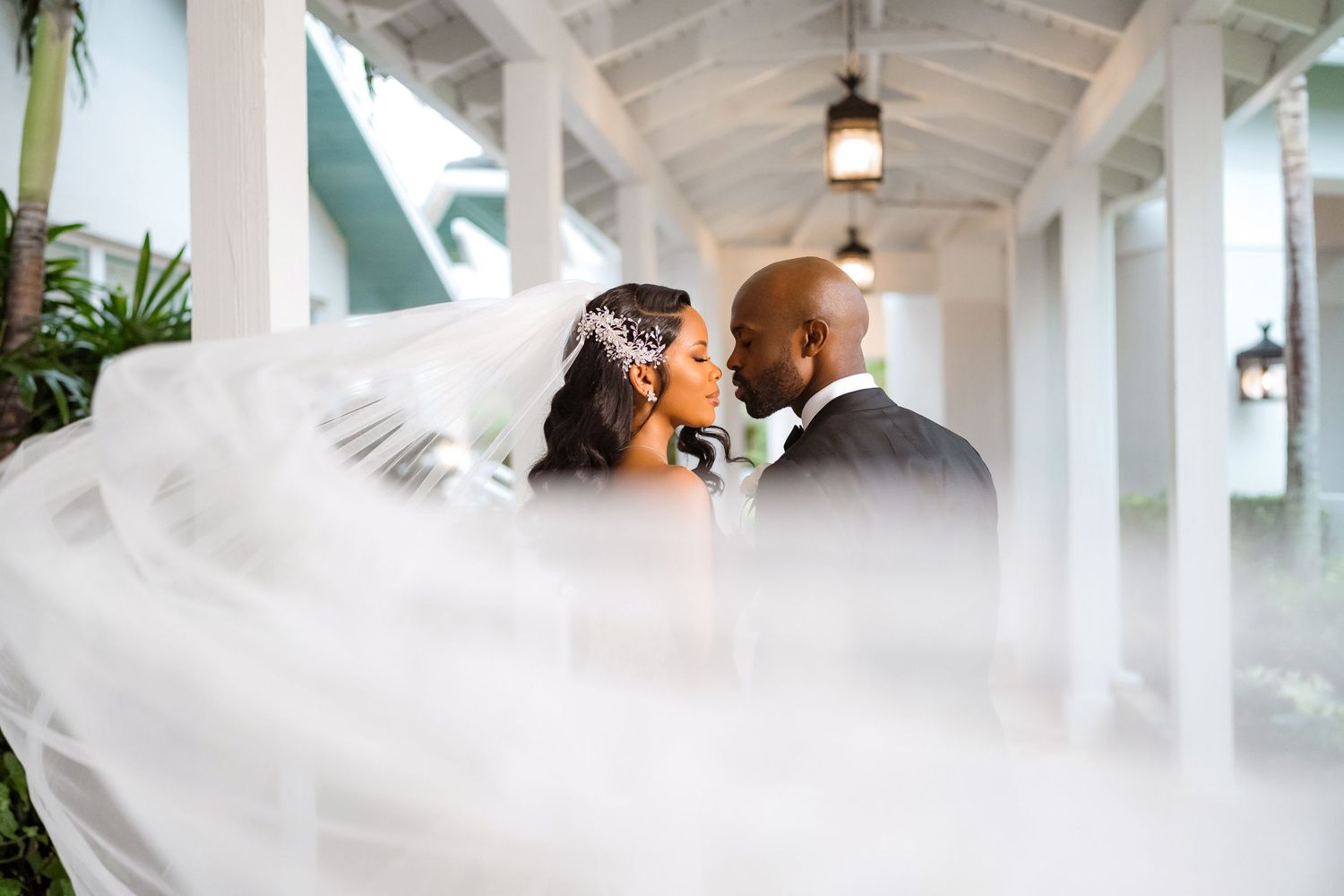 A dreamy wedding photo showing a long flowing veil floating in a white columned hallway.