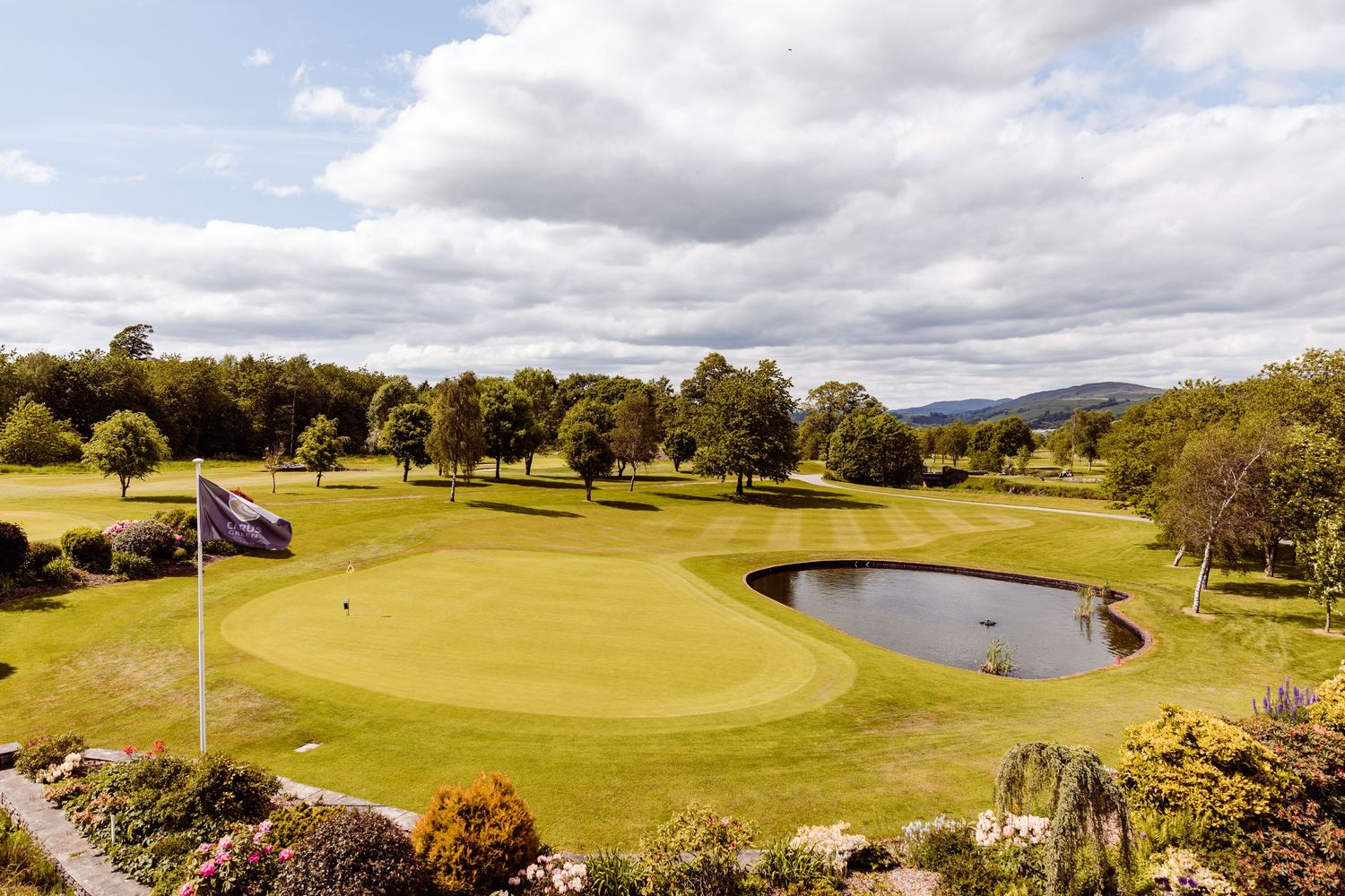 A scenic golf course with well-manicured greens and a heart-shaped pond under cloudy skies.