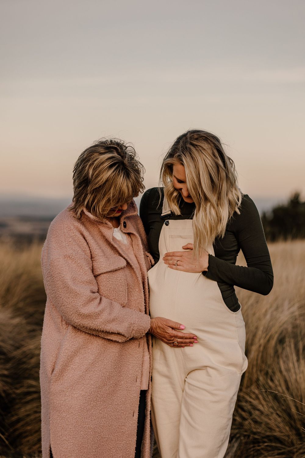 Two people share an emotional moment in a field at sunset.