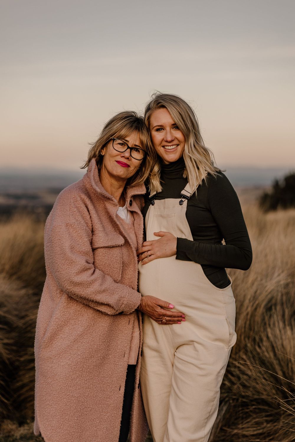 Two people share a tender moment in casual attire during sunset.
