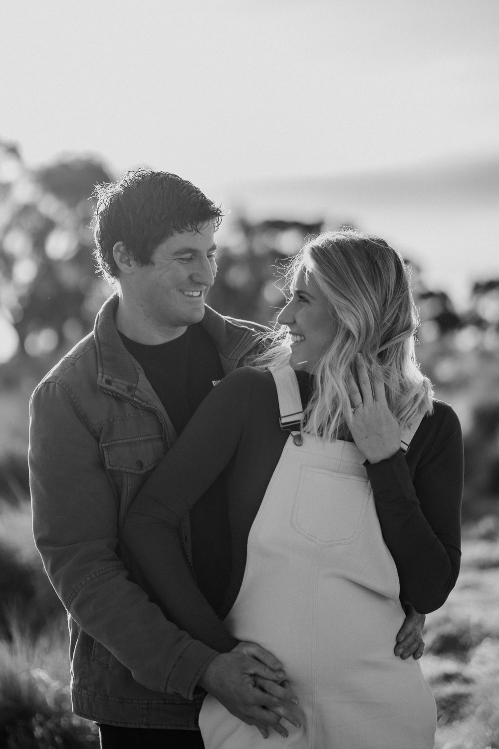 A black and white maternity photo captures an intimate moment between a couple.