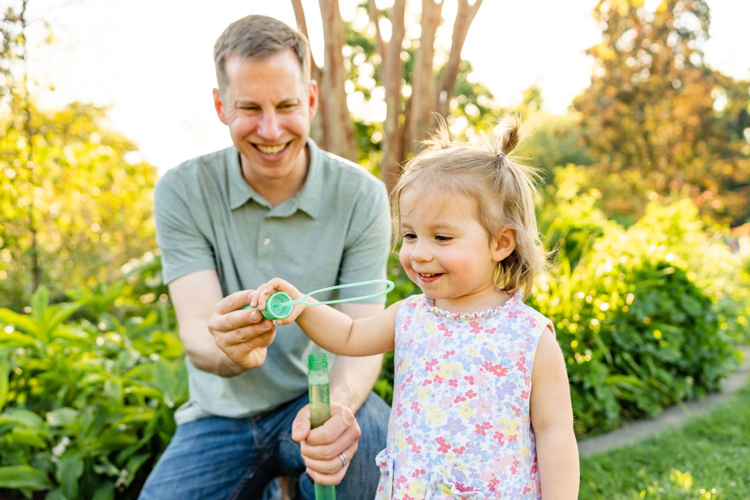 Father and daughter blowing bubbles together at sunset in Bellevue.