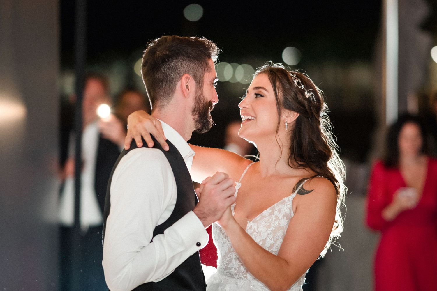 Bride and groom holding hands smilling at eachother while dancing.
