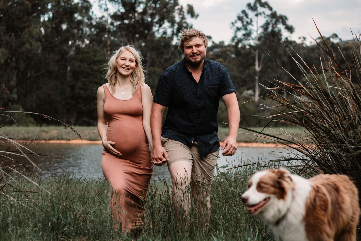 A couple expecting their first child. Pregnant woman, father and a dog by a dam
