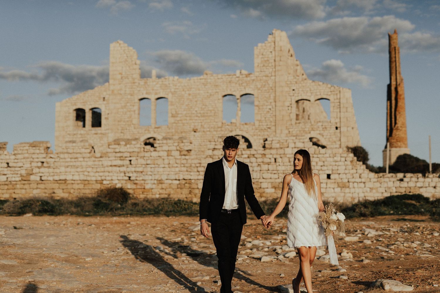 Wedding couple photographed against historic stone ruins in desert landscape.
