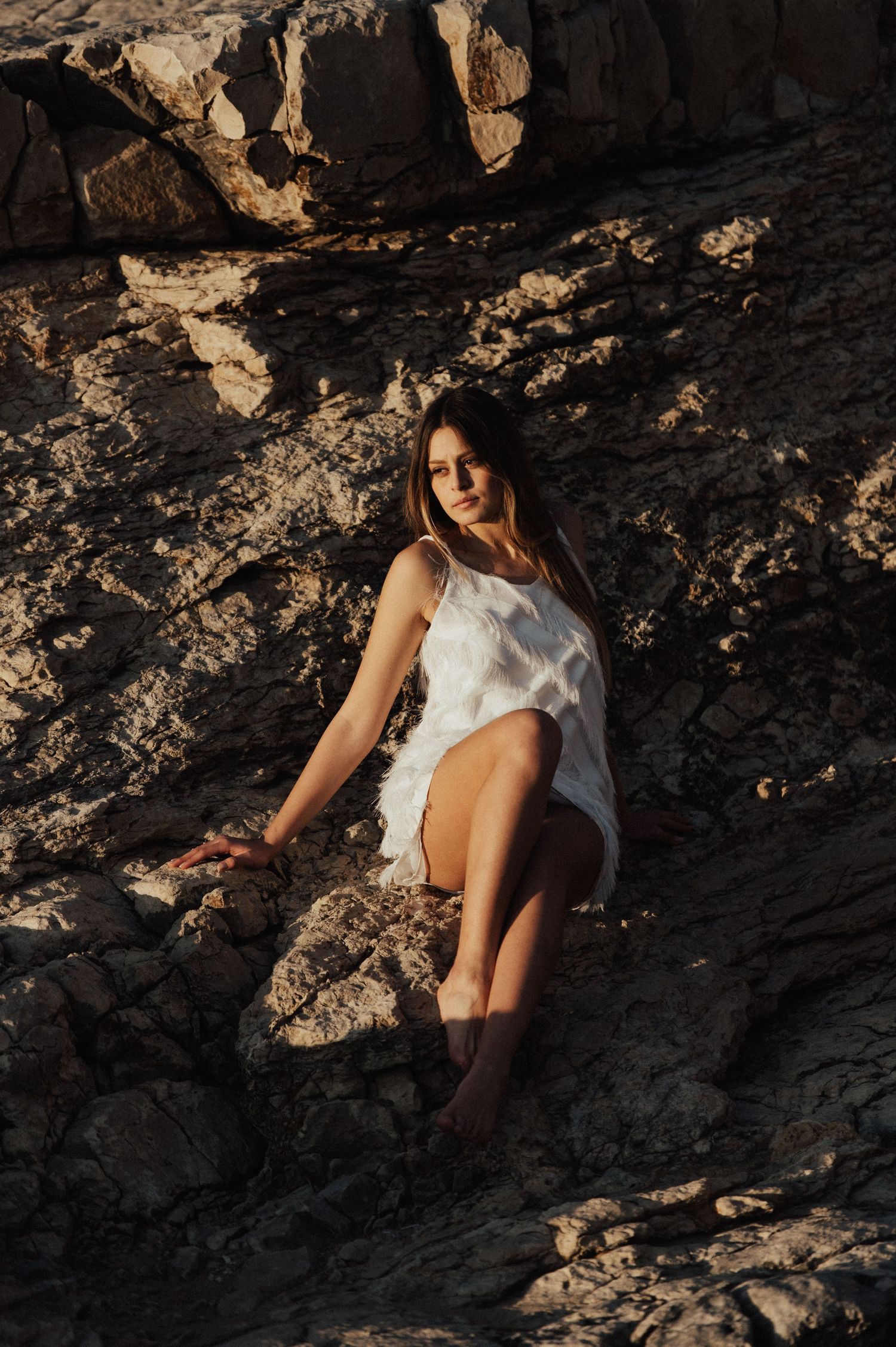 Romantic sunset photoshoot on rocky coastal cliffs with golden light.