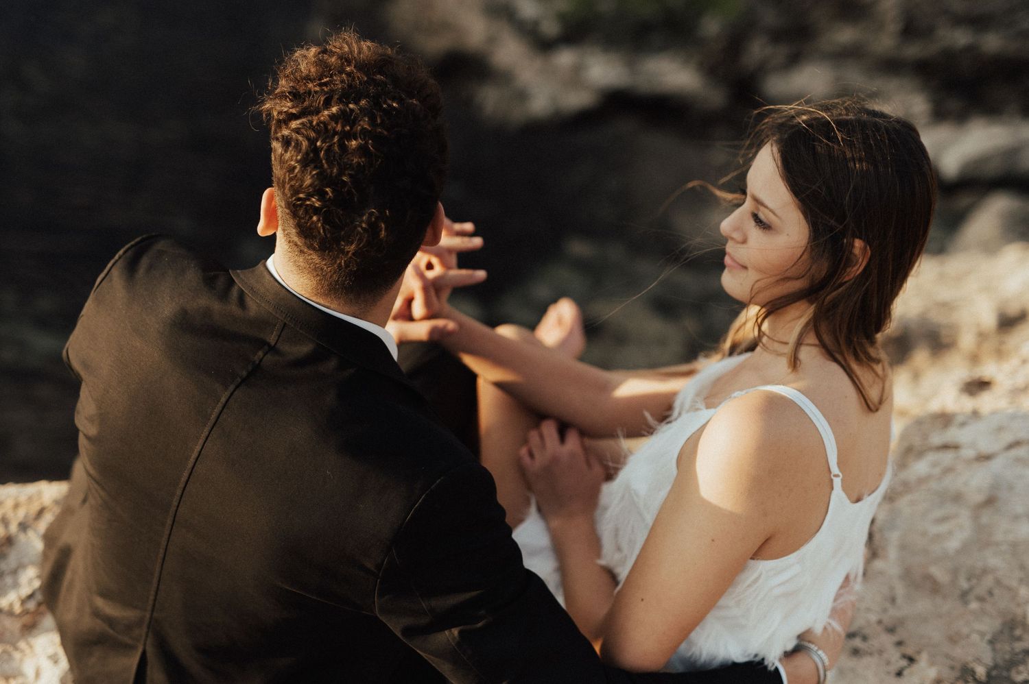 Intimate wedding moment captured against dramatic coastal backdrop at sunset.