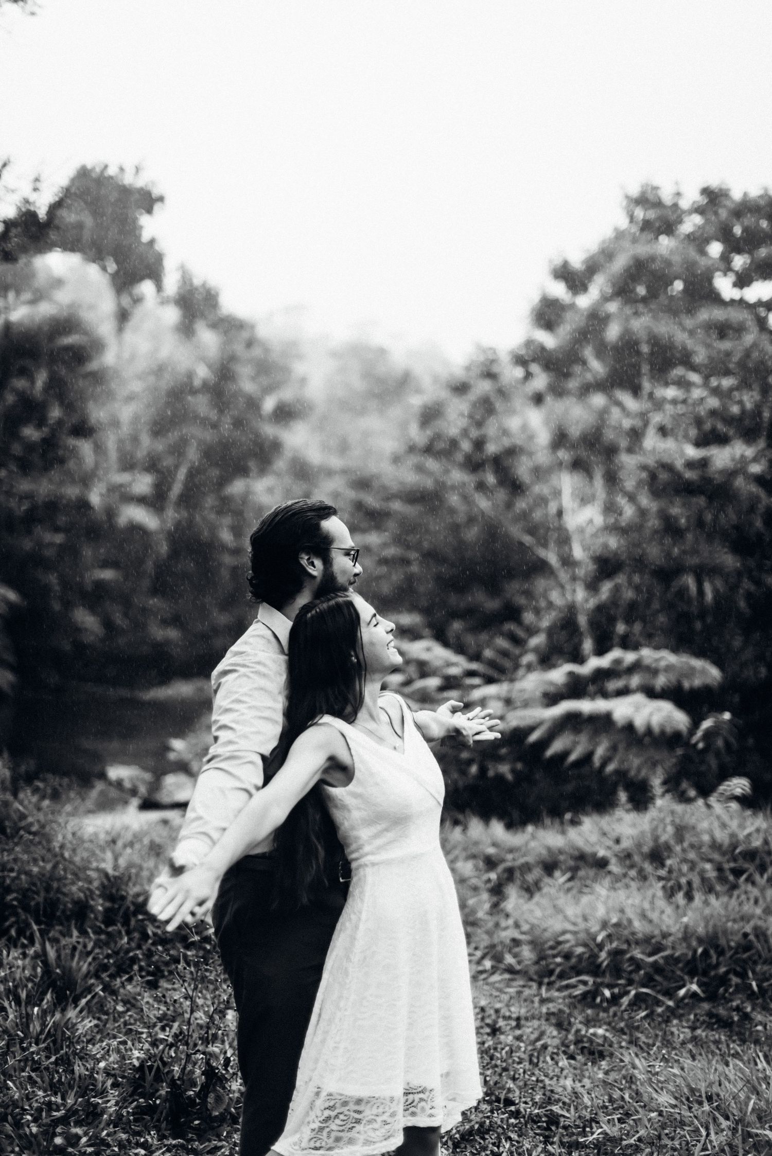 Artistic black and white portrait of a couple embracing in a lush garden setting.