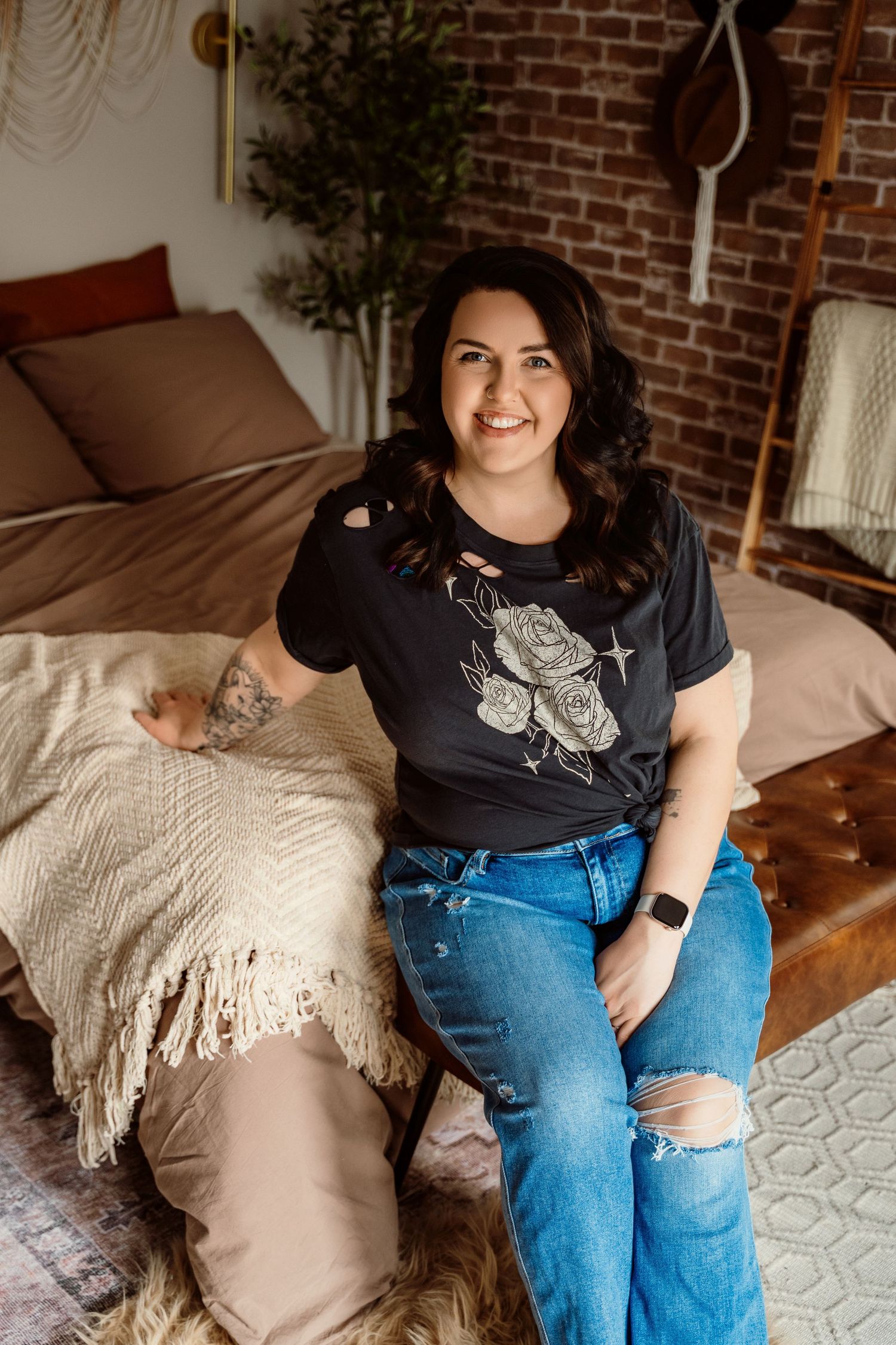 Cozy bedroom scene with grey sweater and jeans on furry rug, with brick wall and potted plant in background.