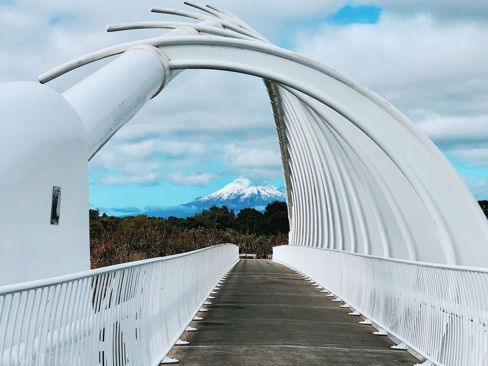 Modern white curved pedestrian bridge with Mount Fuji visible in the distance.