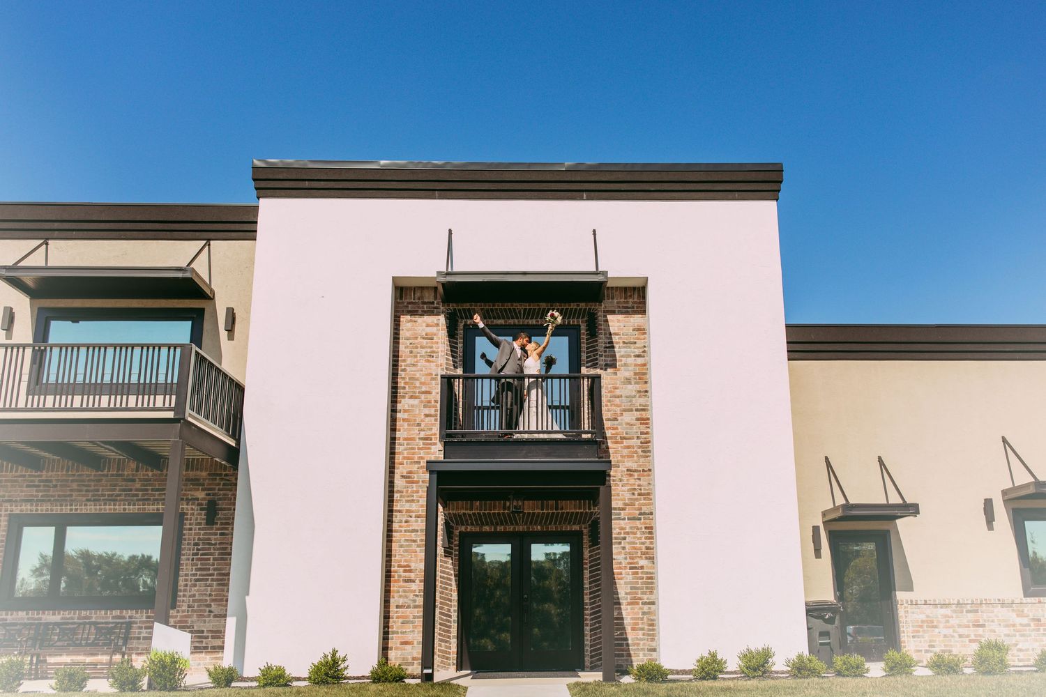 Modern pink and stone facade of an upscale two-story building with large windows.
