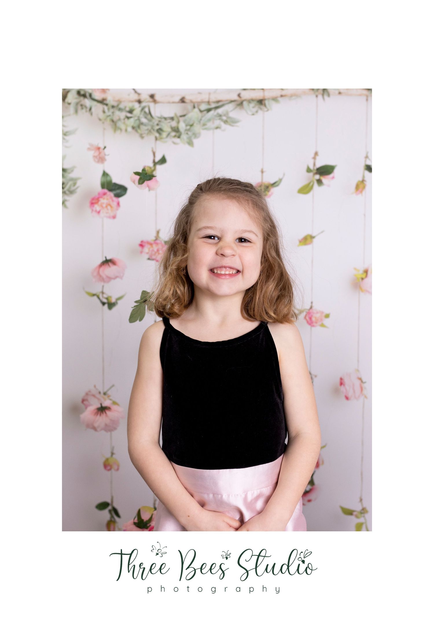 Spring portrait against floral backdrop with dangling pink roses and greenery.