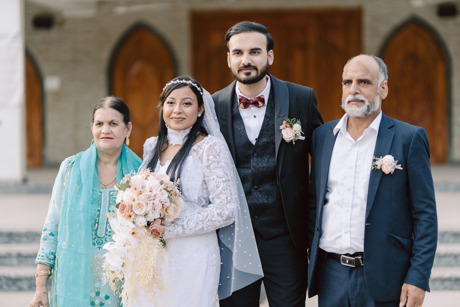 Wedding party gathered outside church entrance in formal attire with mint green accents.