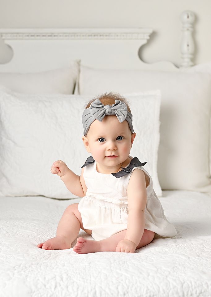 Baby posed sitting on a white bed