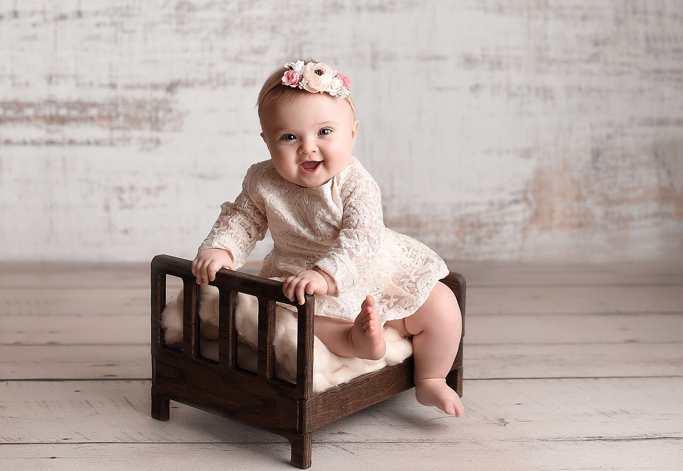 Sitting up baby girl on a bed prop