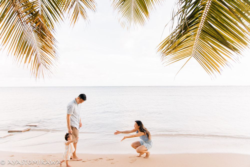 Playful interaction between people on a tropical beach with palm trees framing the scene.
