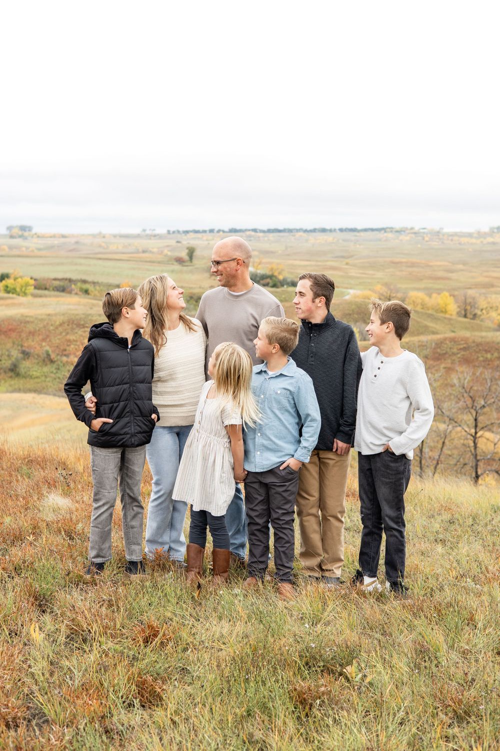 Family group standing together on hilltop overlooking autumn prairie landscape.
