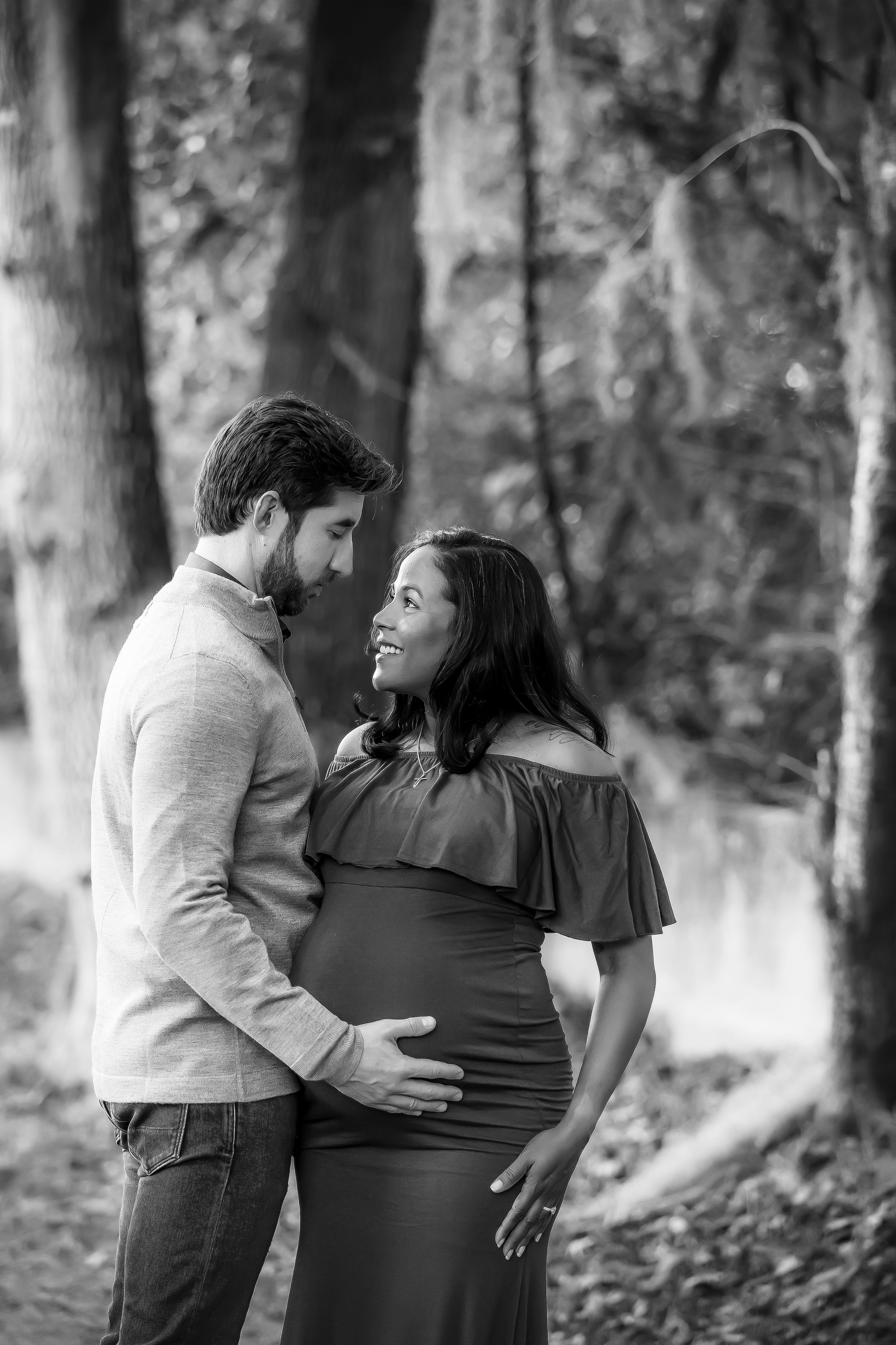 Black and white image of pregnant woman and husband looking at each other.