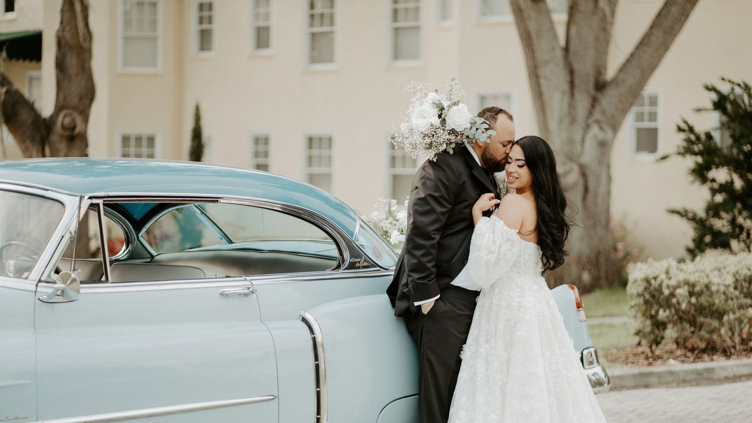a wedding couple posed in front of a vintage blue car at the Lakeside Inn in Mount Dora Florida