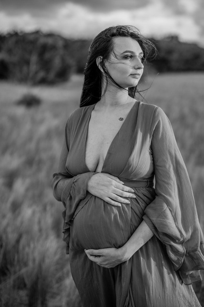 Dramatic black and white maternity portraits in a natural outdoor setting.