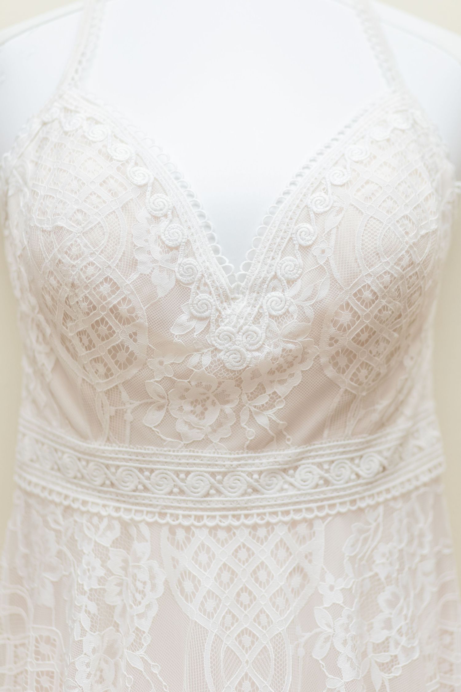 Close-up detail of white lace wedding dress bodice with intricate geometric patterns.