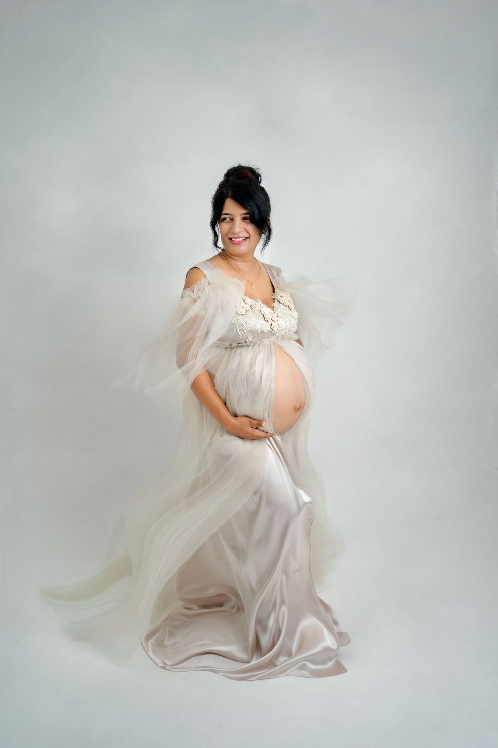 Maternity session featuring elegant white gown with flowing fabric details.