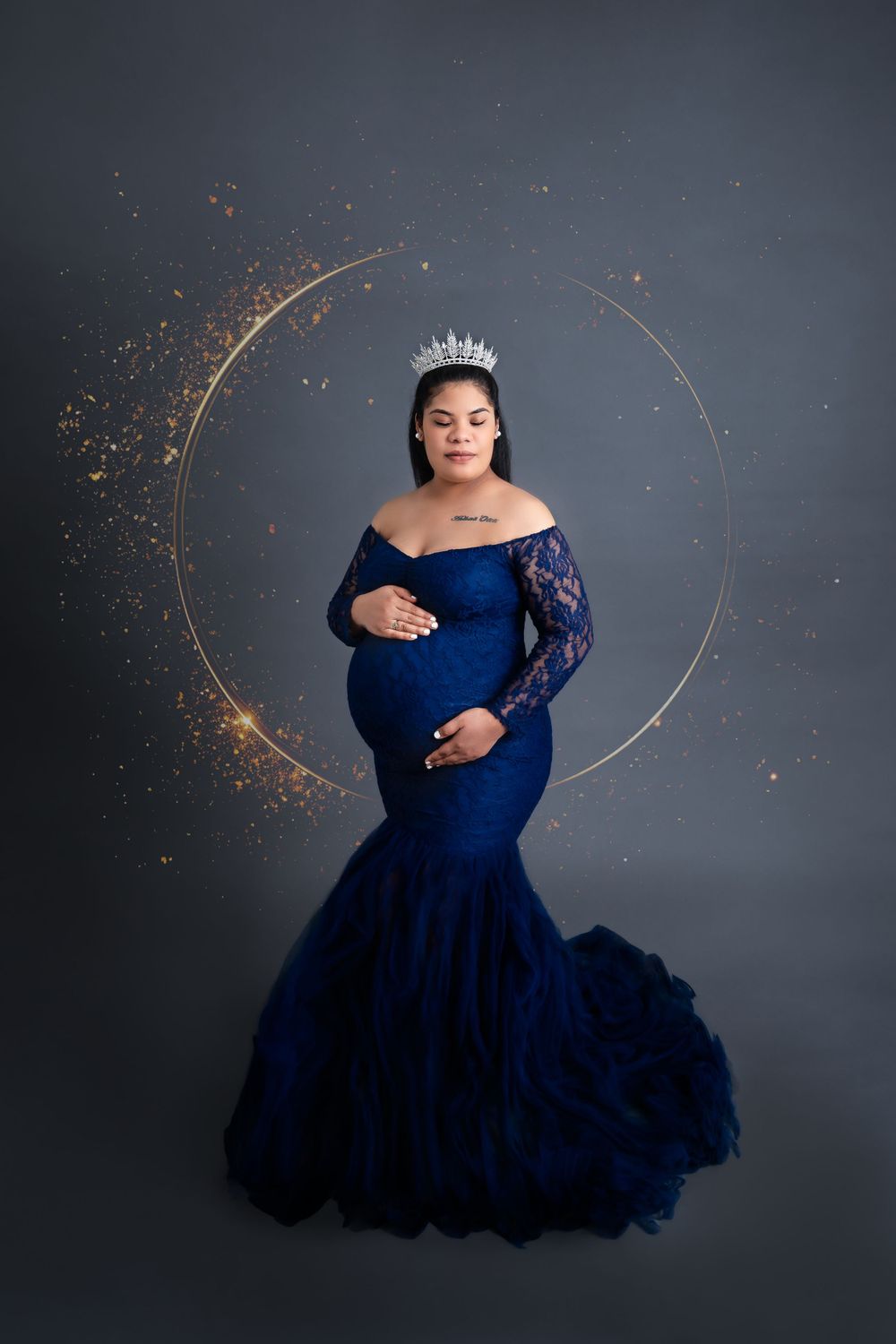 Maternity portrait with sparkler effects and a navy blue gown against grey background.