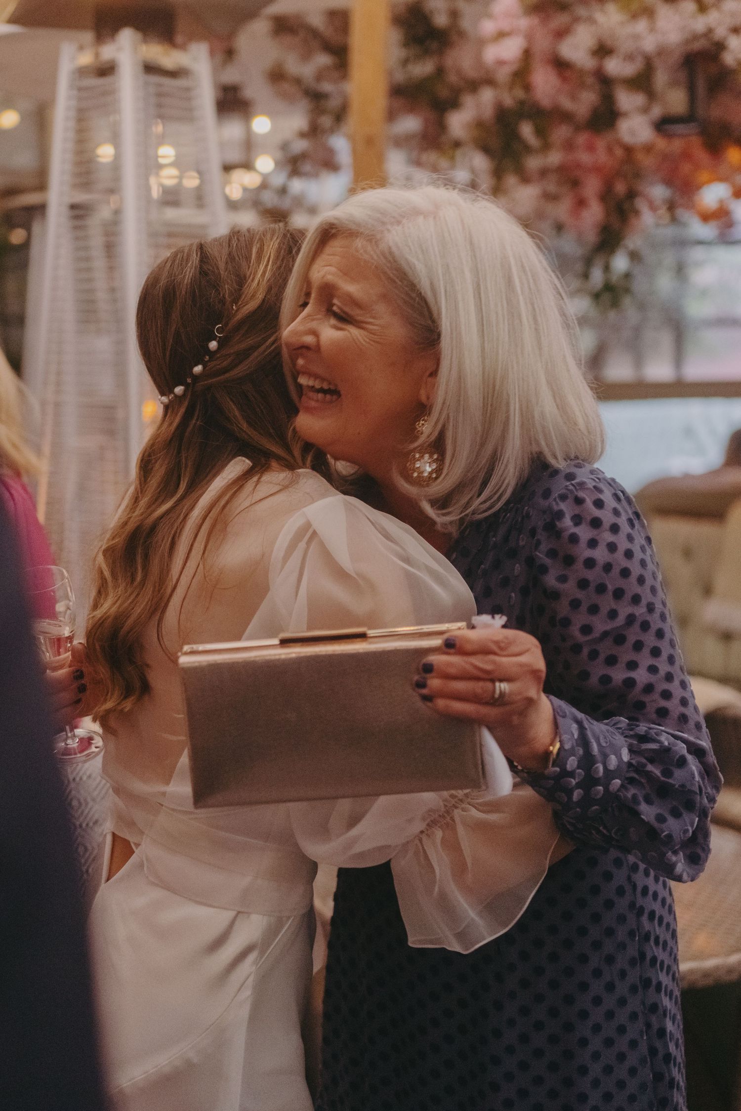 Two people sharing an emotional embrace at an elegant outdoor celebration.