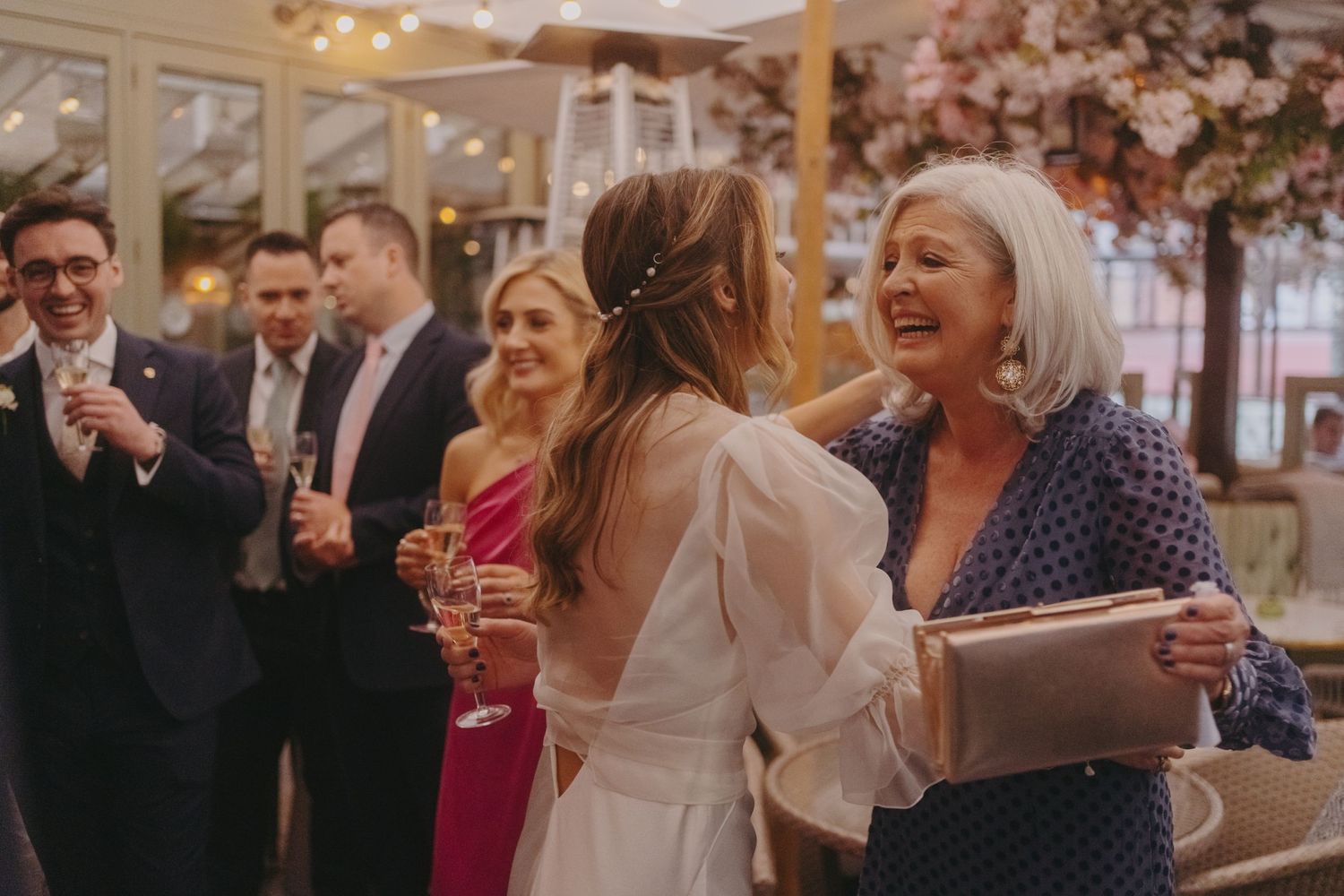 Guests sharing joyful moments at a wedding reception under floral decorations.