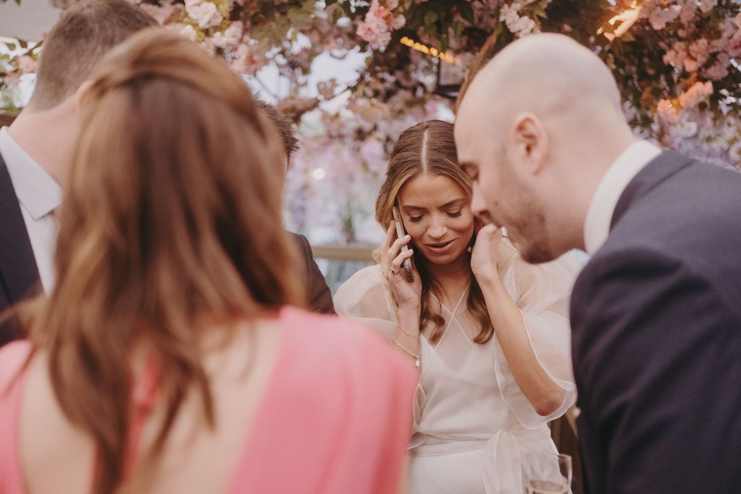 Intimate moment captured during wedding celebration under pink floral arrangements.