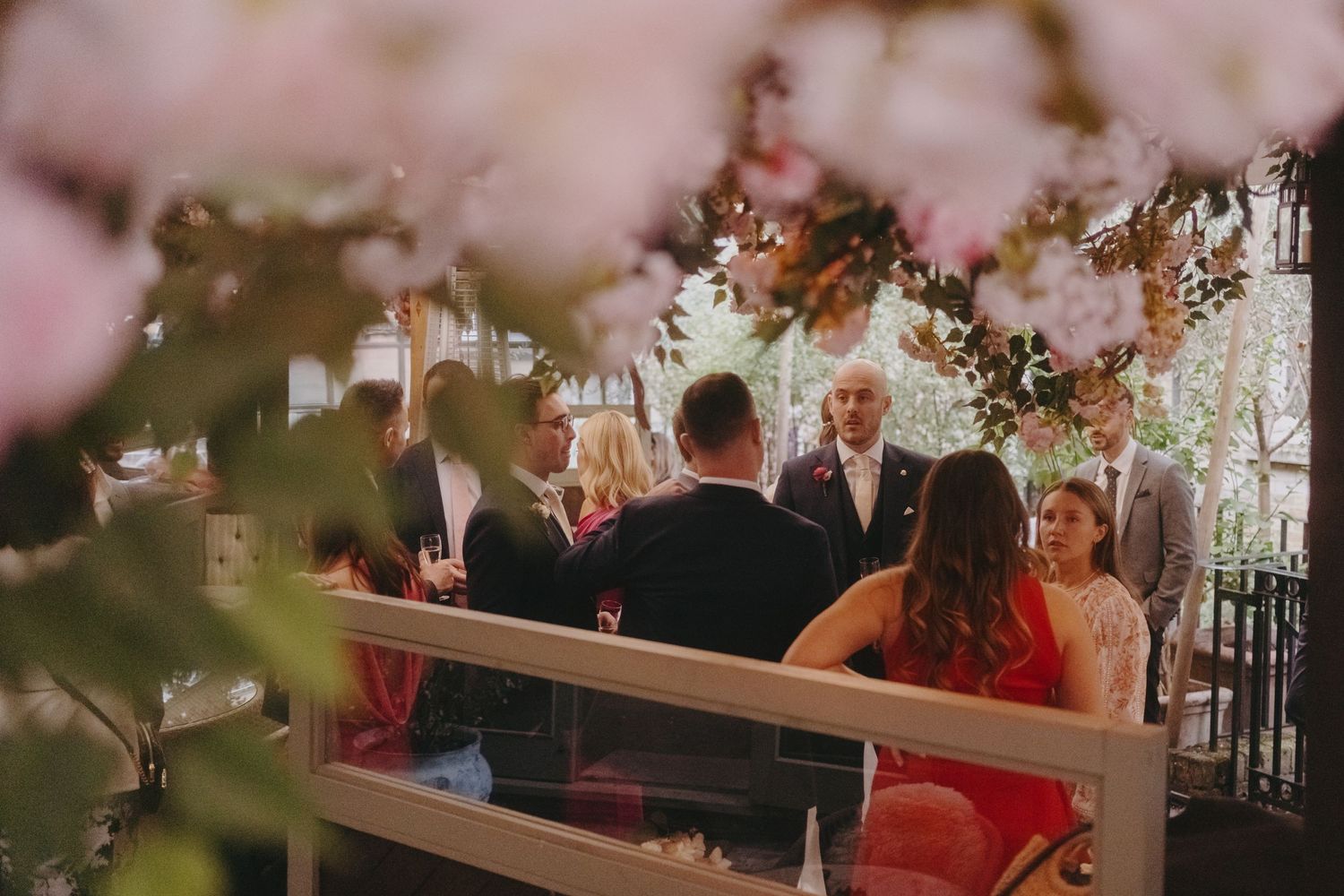 Guests seated at a table during wedding reception with soft pink cherry blossoms in foreground.