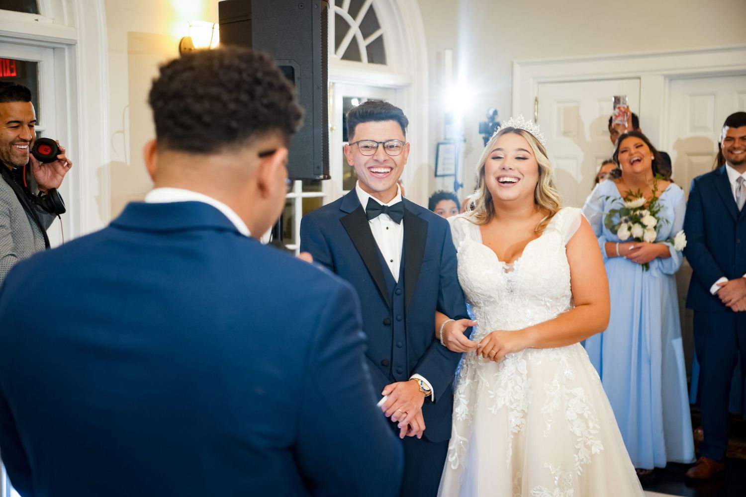 Indoor wedding ceremony with laughter and joy in an elegant white room.