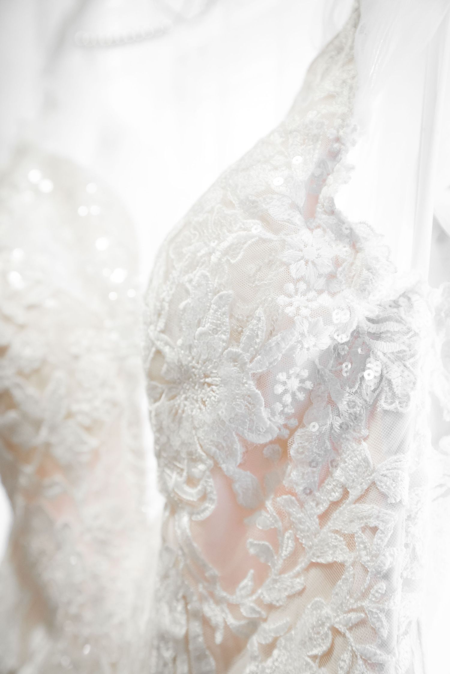 Delicate white lace detail on a wedding dress bodice with intricate floral patterns.
